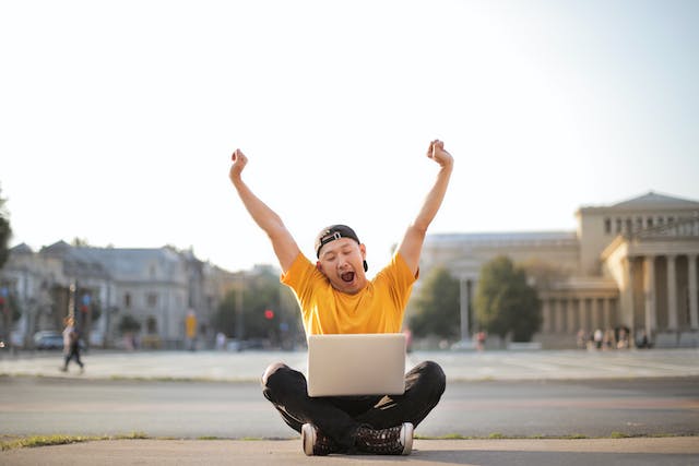 Asian man wearing yellow shirt playing online slots outdoors